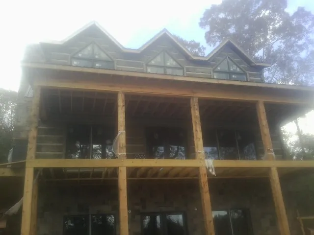 Dormers and porch framing on a large log home under construction — Roof Coating work by our crew in Johnstown