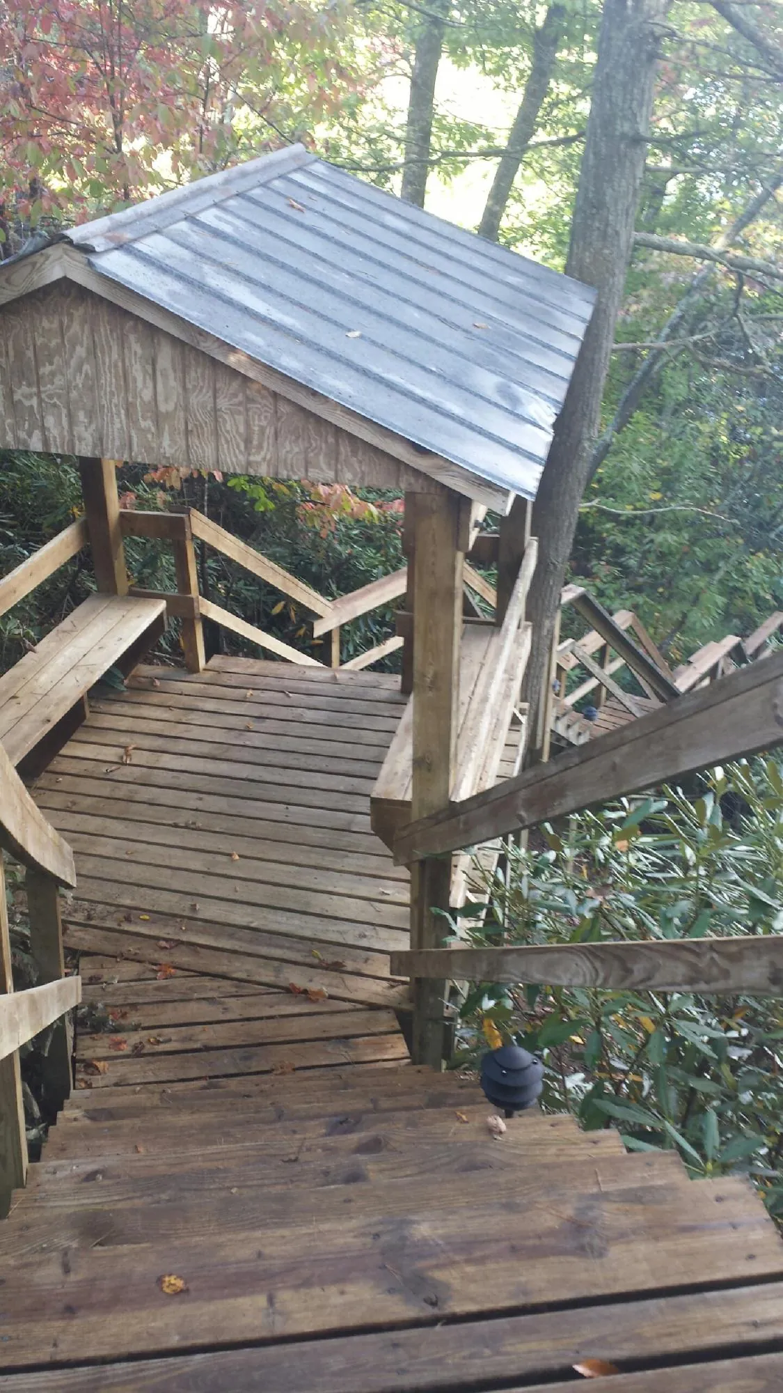 Metal roofed shelter over wooden steps on a wooded walkway — Skylight Repair & Installation work by our crew in Johnstown